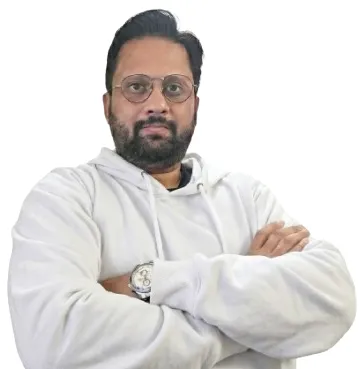 Headshot: Adi Rao — direct, slightly serious expression. Not a studio smile. Face clearly visible. Natural or office light. Could be seated at desk, jacket or casual smart.